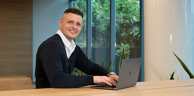 Justin working at his laptop in a bright office